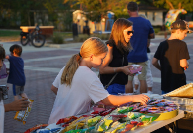 Children and adults choose snacks from a table on Bates Street during National Night Out.