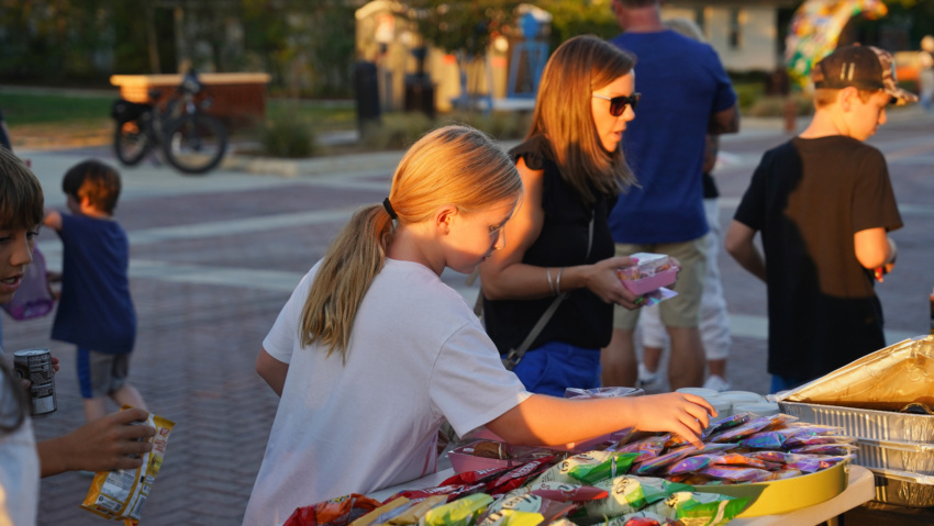 Children and adults choose snacks from a table on Bates Street during National Night Out.