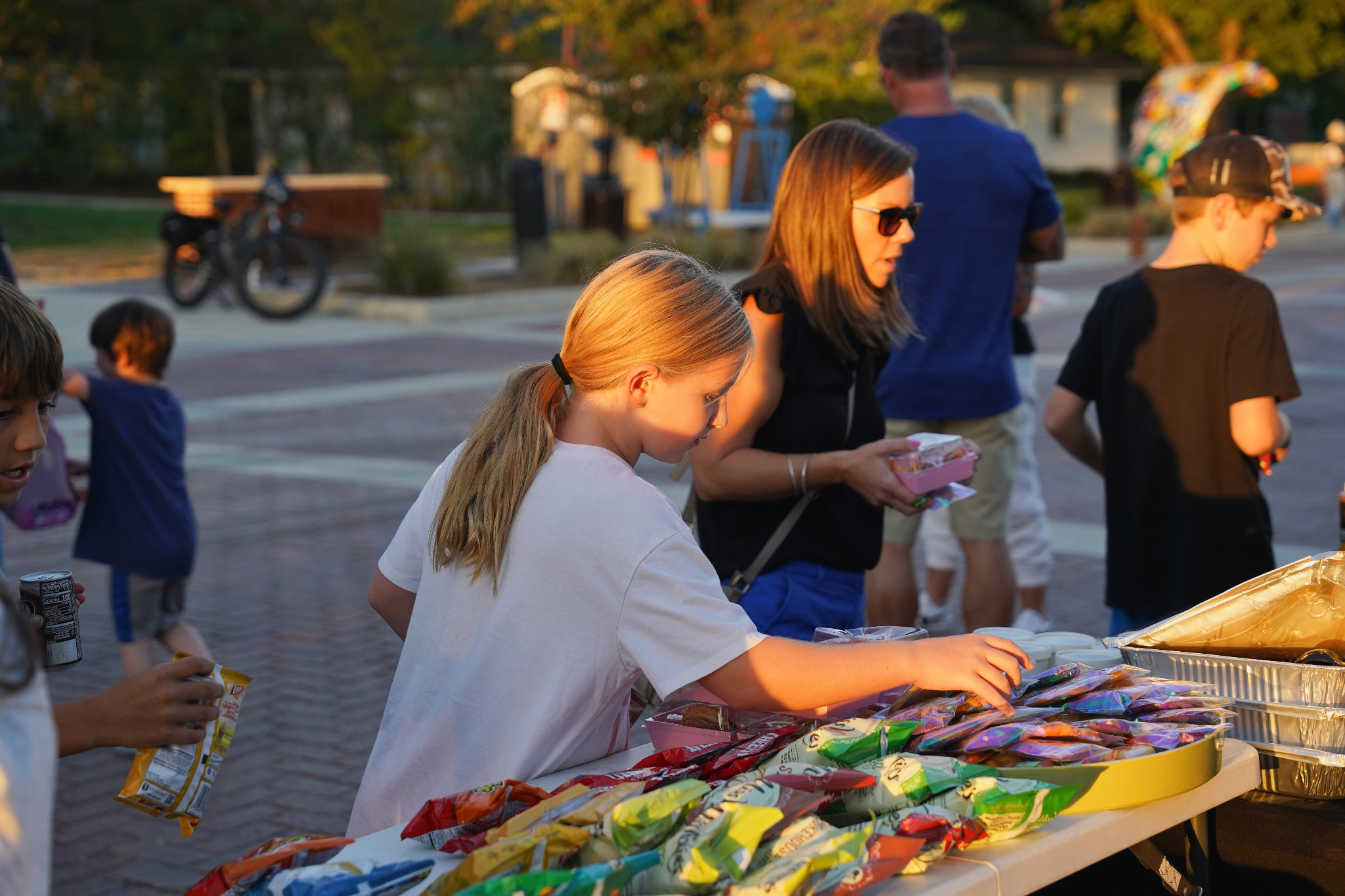 Children and adults choose snacks from a table on Bates Street during National Night Out.